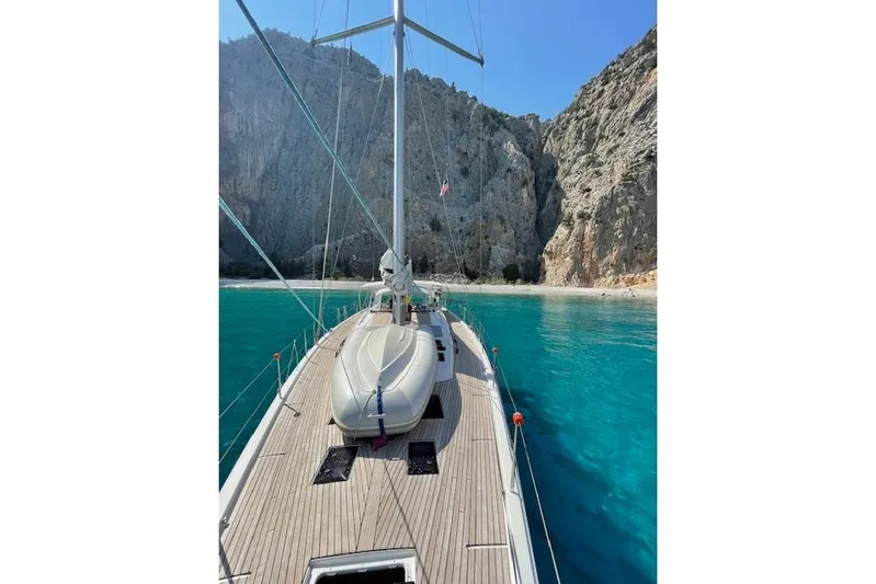  Yacht Photos Pics Dufour 560 Grand Large yacht in turquoise waters near rocky cliffs, 2015 model.
