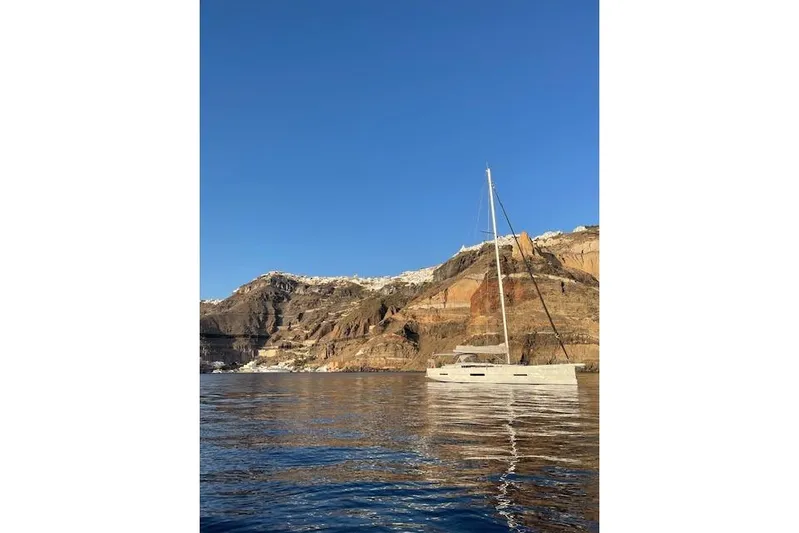  Yacht Photos Pics Sailing yacht Dufour 560 Grand Large 2015 near rocky coastline under clear blue sky.