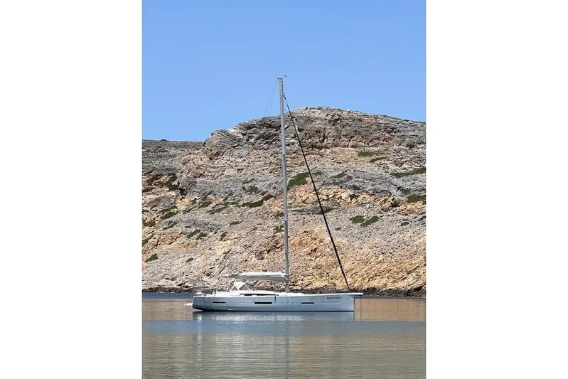  Yacht Photos Pics Sailing yacht Dufour 560 Grand Large 2015 anchored near rocky coastline.