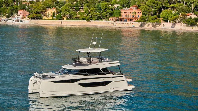  Yacht Photos Pics 2025 Prestige M48 yacht cruising near a scenic coastal town.