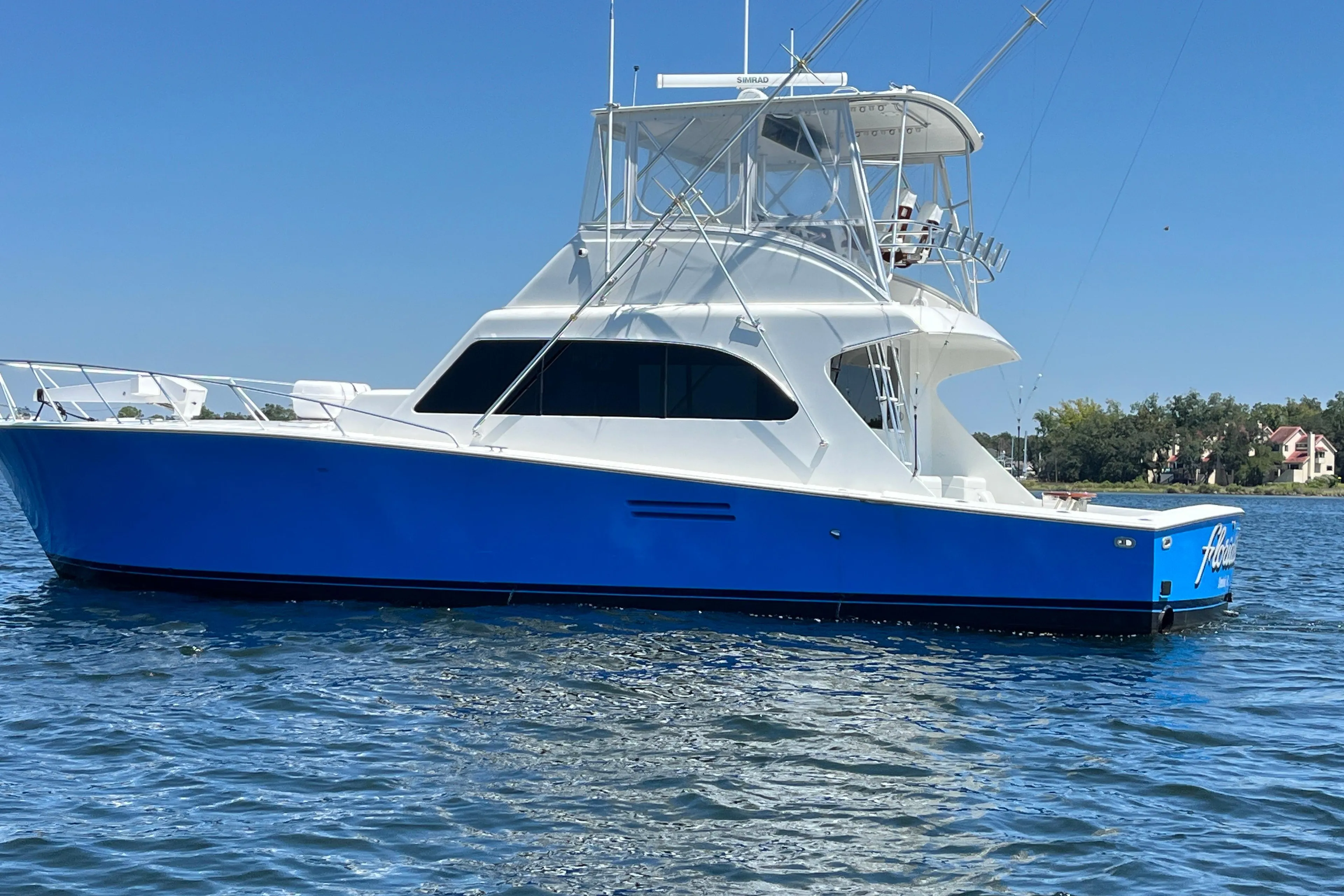 1997 Post Sportfish boat with blue hull on calm water, clear sky background.