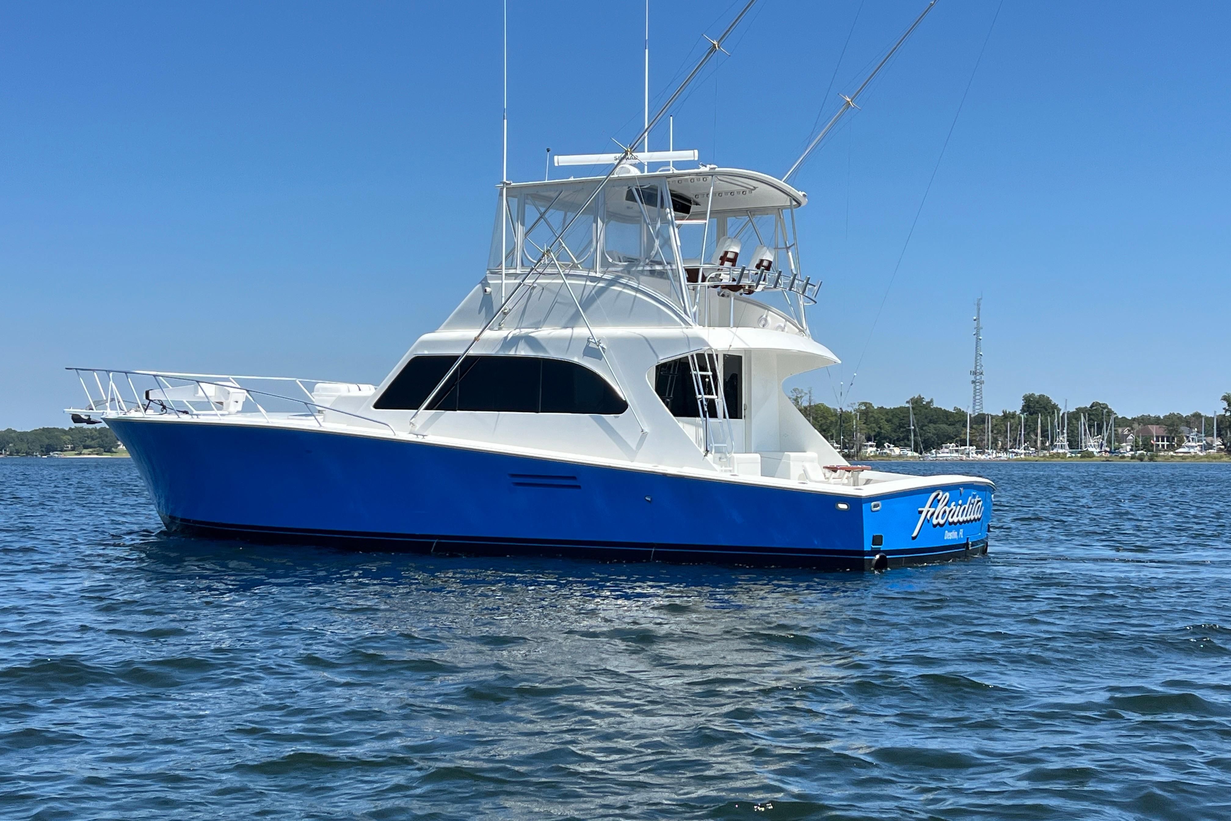 1997 Post Sportfish boat with blue hull on calm water under clear sky.