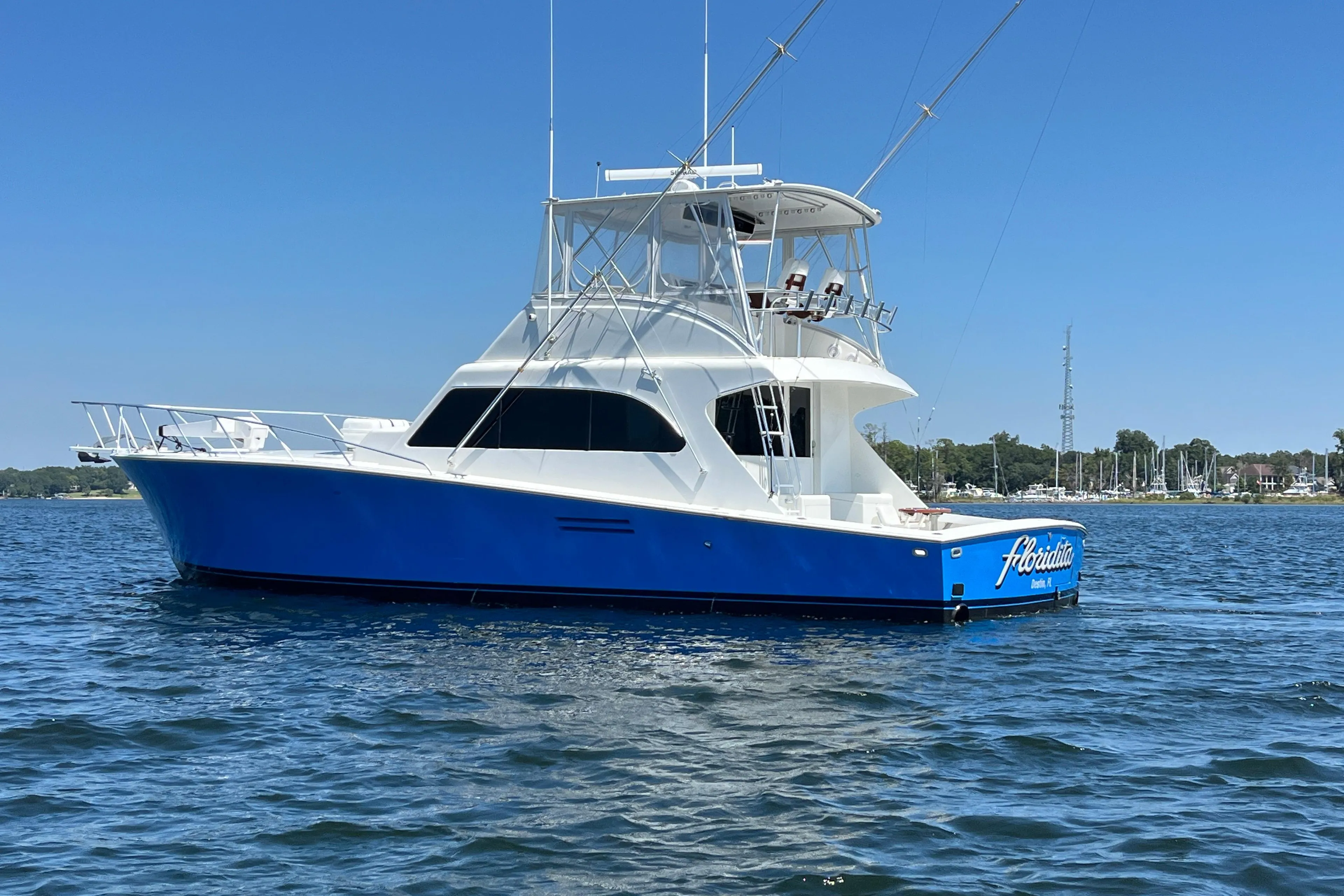1997 Post Sportfish boat with blue hull on calm water under clear sky.