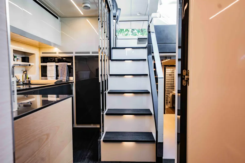  Yacht Photos Pics Modern interior of 2017 Pershing 70 yacht featuring sleek kitchen and illuminated staircase.