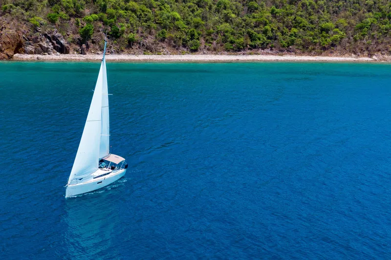 Minx Yacht Photos Pics 2024 Jeanneau Sun Odyssey 349 sailing near lush coastline in clear blue waters.