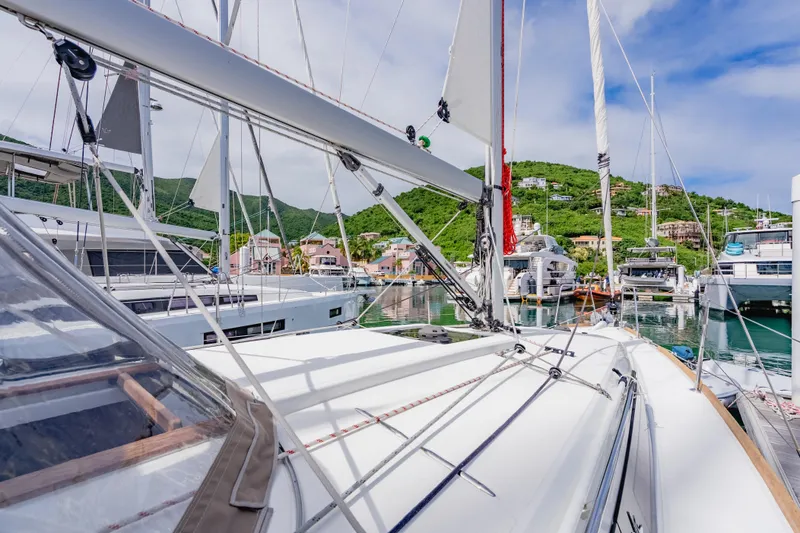 Minx Yacht Photos Pics 2024 Jeanneau Sun Odyssey 349 sailboat docked in a scenic marina with lush hills.