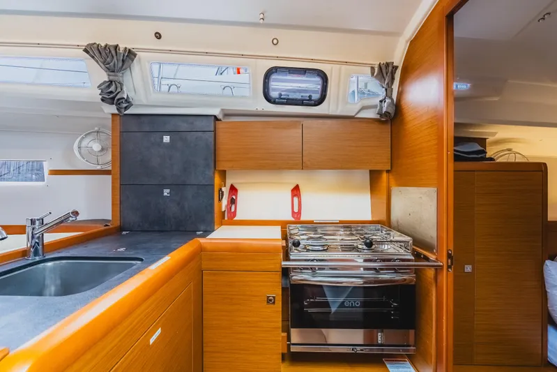 Minx Yacht Photos Pics Modern kitchen interior of 2024 Jeanneau Sun Odyssey 349 yacht, featuring sleek wood cabinetry.