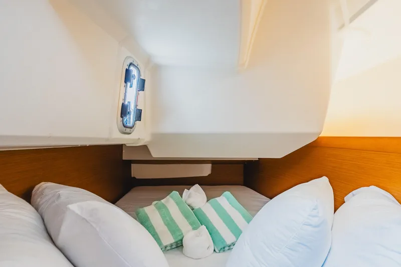 Minx Yacht Photos Pics Cozy cabin interior of 2024 Jeanneau Sun Odyssey 349 sailboat with pillows and window.