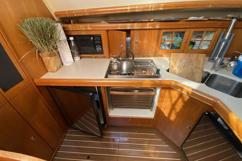 Dolce Vita Yacht Photos Pics 2004 Hunter 41 AC yacht kitchen with wooden cabinetry, stove, and sink.