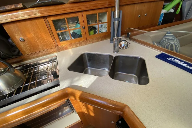 Dolce Vita Yacht Photos Pics Galley kitchen in 2004 Hunter 41 AC sailboat with dual sinks and wooden cabinetry.