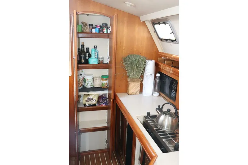 Dolce Vita Yacht Photos Pics 2004 Hunter 41 AC yacht kitchen with wooden cabinets, stove, and pantry shelves.