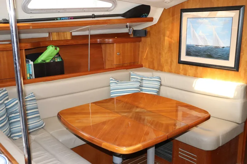 Dolce Vita Yacht Photos Pics Cozy interior of 2004 Hunter 41 AC sailboat with wooden table and striped cushions.
