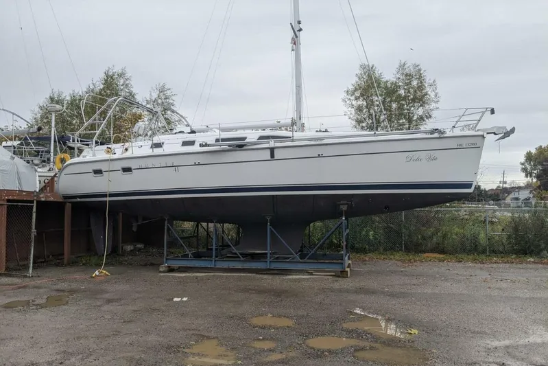 Dolce Vita Yacht Photos Pics 2004 Hunter 41 AC sailboat on dry dock, surrounded by trees and overcast sky.