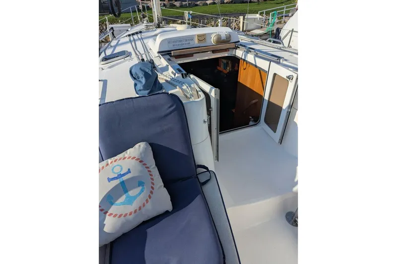 Dolce Vita Yacht Photos Pics 2004 Hunter 41 AC sailboat deck with open cabin door and nautical-themed cushion.