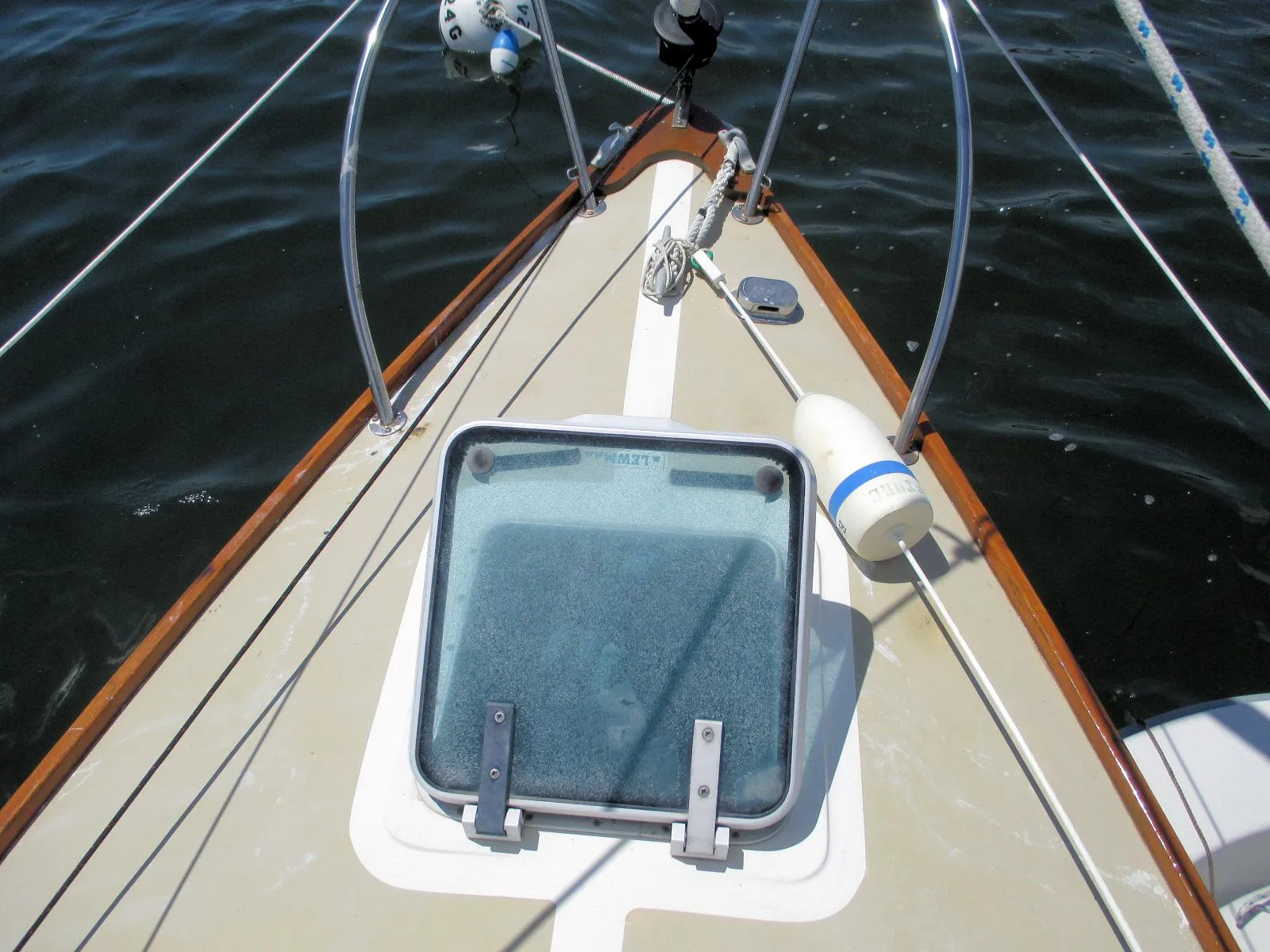 Bow of 1988 Quickstep 24 sailboat with hatch and railing on water.