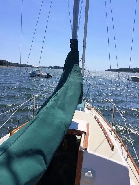 Sailboat on open water, Quickstep 24 model, 1988, with green sail cover, sunny day.