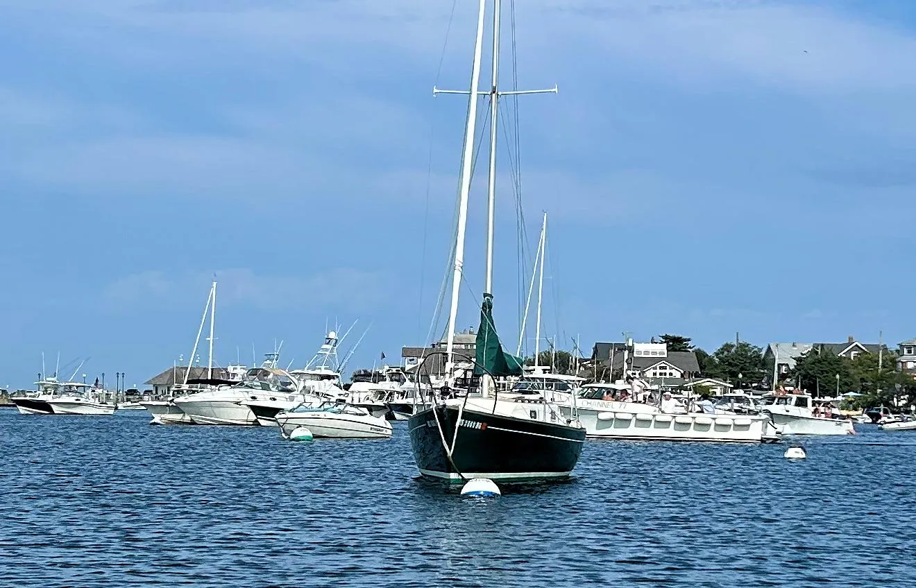 Sailboat Quickstep 24 (1988) anchored in a bustling marina under a clear blue sky.