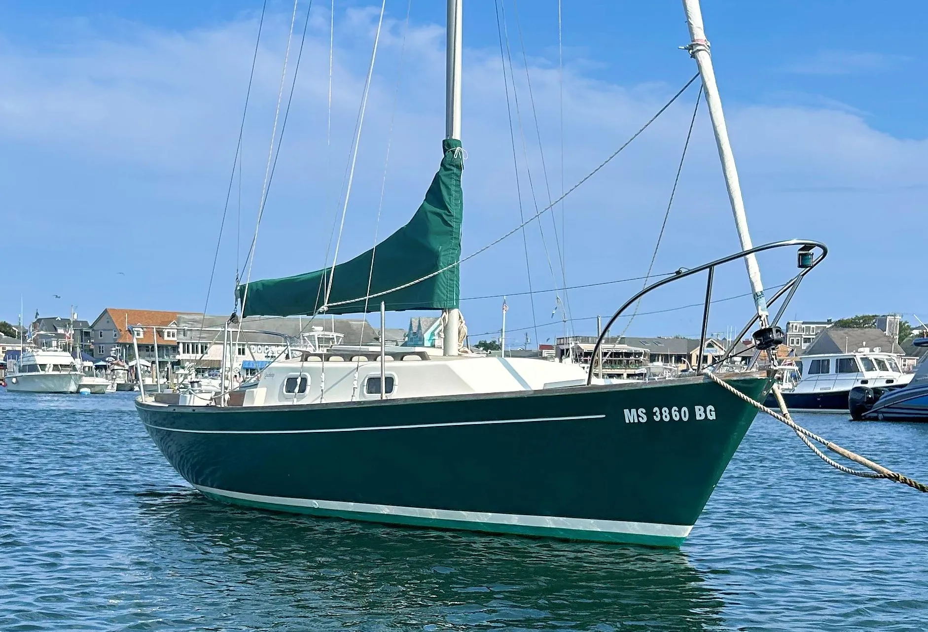 1988 Quickstep 24 sailboat docked in a marina, featuring a green hull and sail cover.