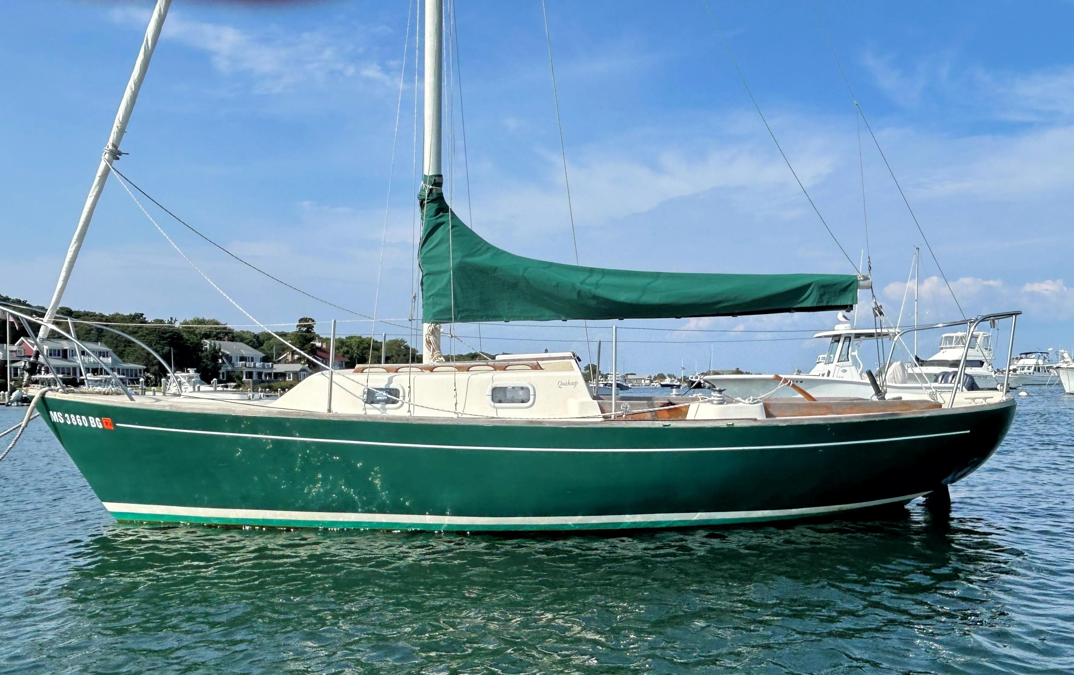 Green 1988 Quickstep 24 sailboat anchored in a scenic harbor.