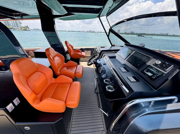 La Doña Yacht Photos Pics 2023 Pardo Yachts 50 cockpit with orange seats and modern dashboard, overlooking the ocean.