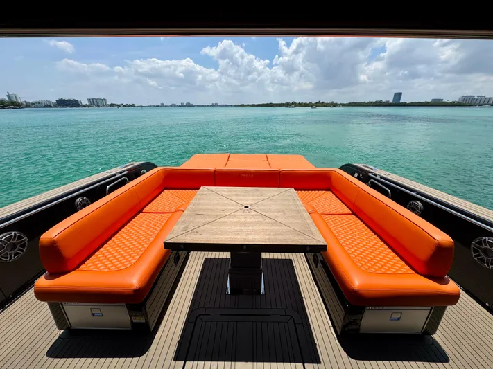 La Doña Yacht Photos Pics 2023 Pardo Yachts 50 with orange seating, wooden table, overlooking serene turquoise waters.