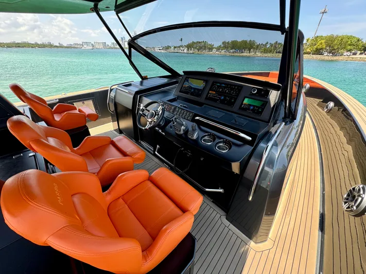 La Doña Yacht Photos Pics 2023 Pardo Yachts 50 cockpit with orange seats and modern controls, overlooking turquoise waters.