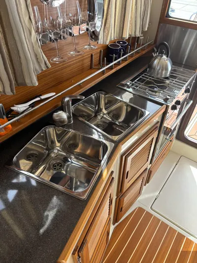  Yacht Photos Pics 2024 Ranger Tugs R31S kitchen with dual sinks, stove, and wooden cabinetry.