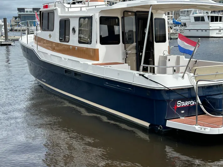  Yacht Photos Pics 2024 Ranger Tugs R31S boat docked, featuring a sleek design and vibrant flag.