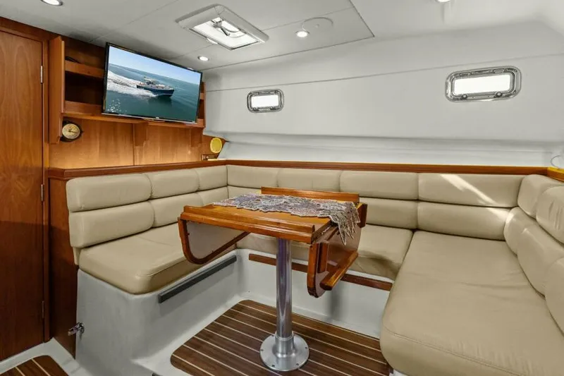 Whattakeeper Yacht Photos Pics Interior of 2006 Mainship 34 Rum Runner II with beige seating and wooden table.