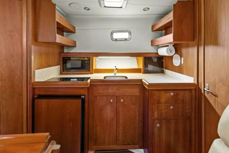 Whattakeeper Yacht Photos Pics 2006 Mainship 34 Rum Runner II galley with wood cabinetry, sink, and appliances.