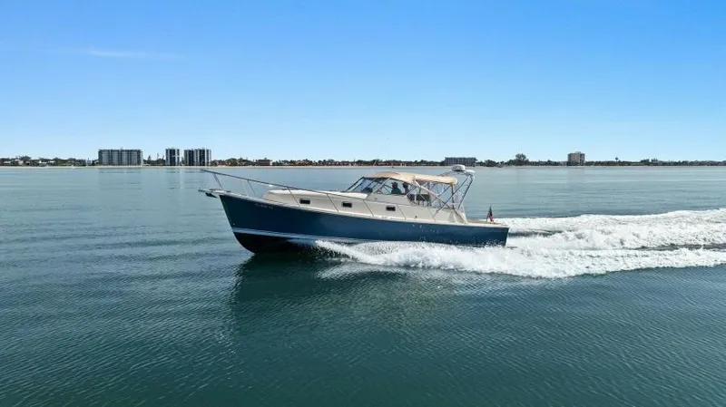 Whattakeeper Yacht Photos Pics 2006 Mainship 34 Rum Runner II cruising on calm waters under clear blue sky.