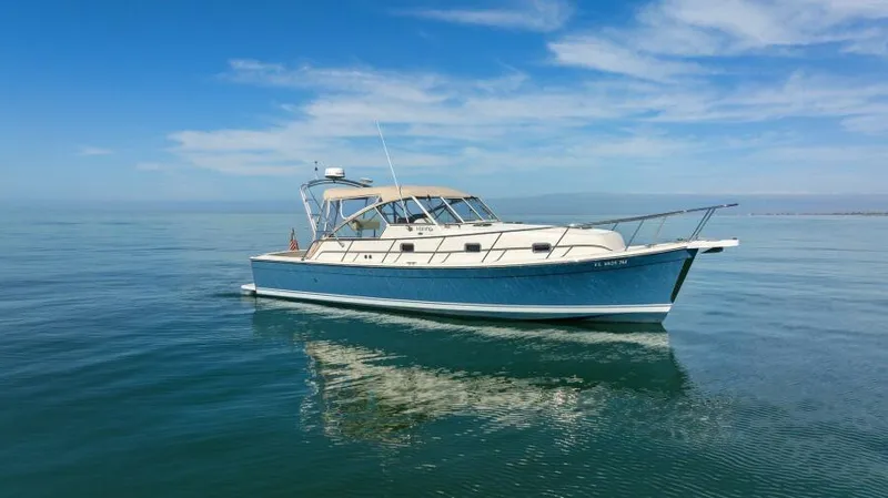 Whattakeeper Yacht Photos Pics 2006 Mainship 34 Rum Runner II cruising on calm waters under a clear blue sky.