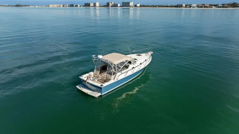 Whattakeeper Yacht Photos Pics 2006 Mainship 34 Rum Runner II cruising on calm waters near a coastal cityscape.