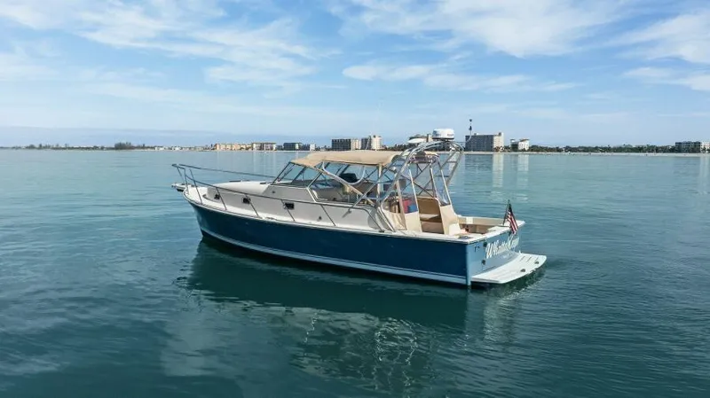 Whattakeeper Yacht Photos Pics 2006 Mainship 34 Rum Runner II boat on calm water with city skyline.