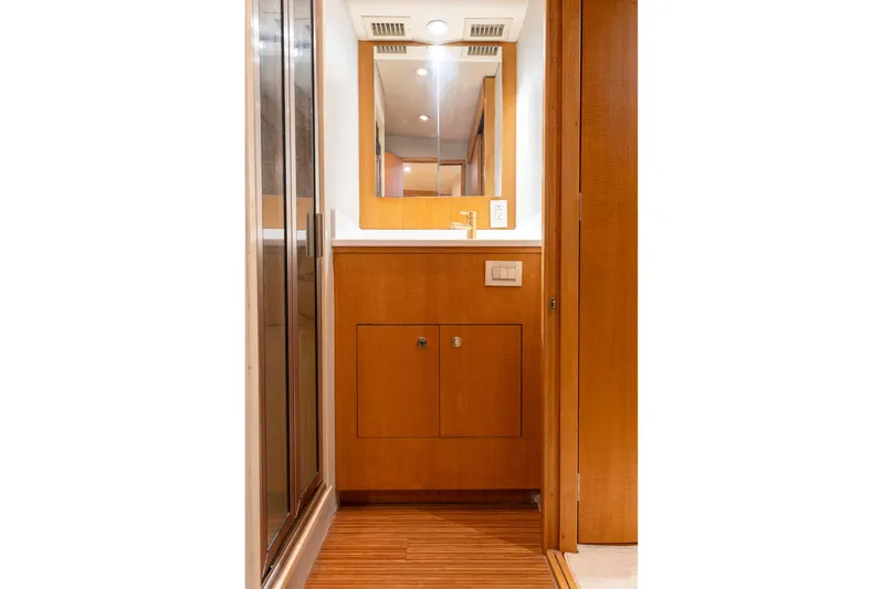 Custom Yacht Photos Pics Wood-paneled bathroom interior of 2005 Weaver 61 yacht with mirror and storage cabinet.