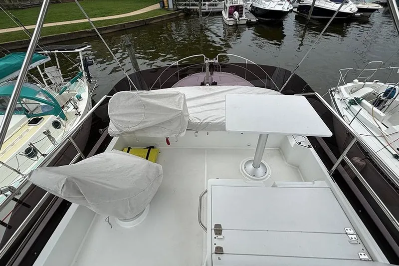  Yacht Photos Pics 2022 Jeanneau NC Weekender 1095 Fly, flybridge view, docked with covered seating and table.