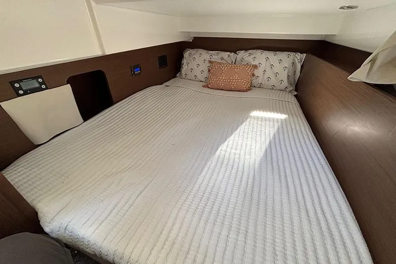  Yacht Photos Pics Cozy cabin bed in 2022 Jeanneau NC Weekender 1095 Fly, featuring elegant wood paneling.