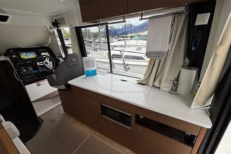  Yacht Photos Pics Interior of 2022 Jeanneau NC Weekender 1095 Fly, featuring helm and kitchenette.