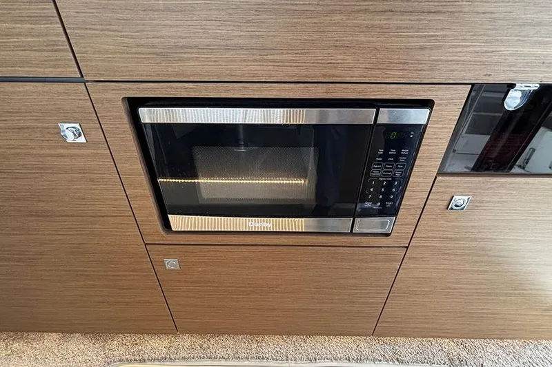  Yacht Photos Pics Built-in microwave in Jeanneau NC Weekender 1095 Fly, 2022 model, with wood paneling.