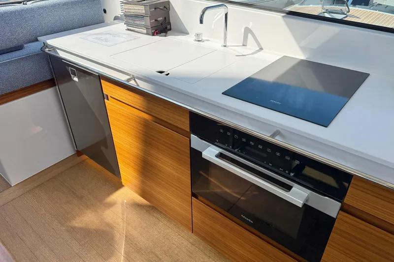  Yacht Photos Pics Modern kitchen interior of 2026 Delta Powerboats 48 Coupe, featuring sleek appliances and wood cabinetry.