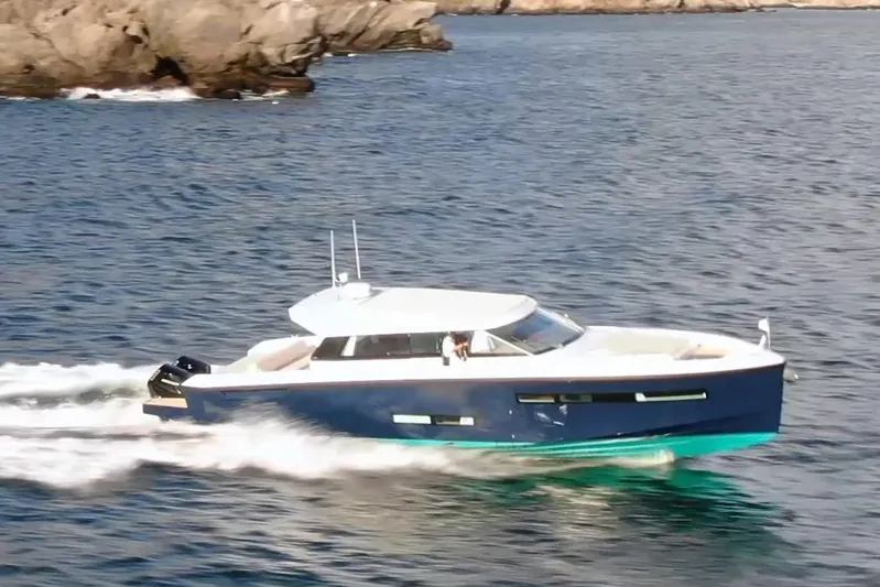  Yacht Photos Pics 2026 Delta Powerboats 48 Coupe cruising on open water near rocky coastline.