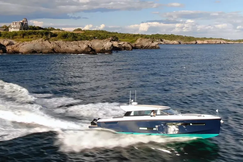  Yacht Photos Pics Delta Powerboats 48 Coupe 2026 cruising near rocky coastline under blue sky.