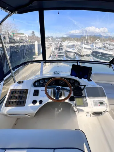 Rising Tide Yacht Photos Pics 1996 Sea Ray 400 Sedan Bridge helm with wooden steering wheel, marina view, and navigation equipment.