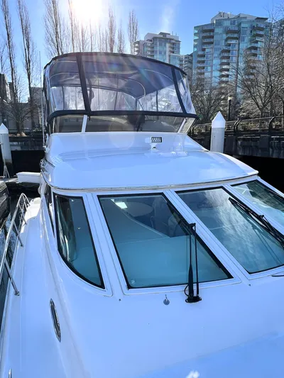 Rising Tide Yacht Photos Pics 1996 Sea Ray 400 Sedan Bridge yacht docked, with cityscape background and clear blue sky.
