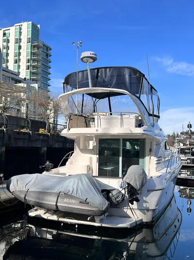 Rising Tide Yacht Photos Pics 1996 Sea Ray 400 Sedan Bridge yacht docked in urban marina, clear blue sky.