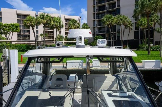 325 Boston Whaler W/ Seakeeper Stabilizer & Ride Yacht Photos Pics 2020 Boston Whaler 325 Conquest docked near palm trees and buildings.