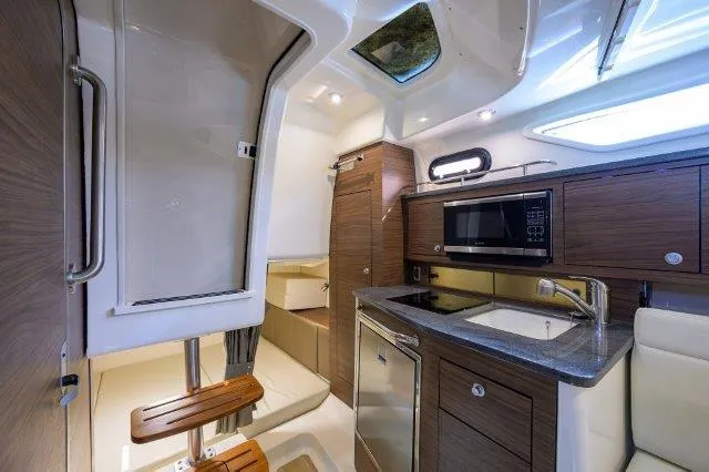 325 Boston Whaler W/ Seakeeper Stabilizer & Ride Yacht Photos Pics 2020 Boston Whaler 325 Conquest cabin interior with kitchenette, microwave, and seating area.