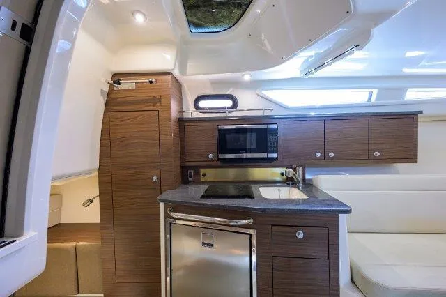 325 Boston Whaler W/ Seakeeper Stabilizer & Ride Yacht Photos Pics 2020 Boston Whaler 325 Conquest interior with modern kitchen, wood cabinetry, and stainless steel appliances.