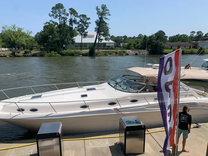  Yacht Photos Pics 1998 Sea Ray 450 Sundancer yacht docked by a river with trees in the background.