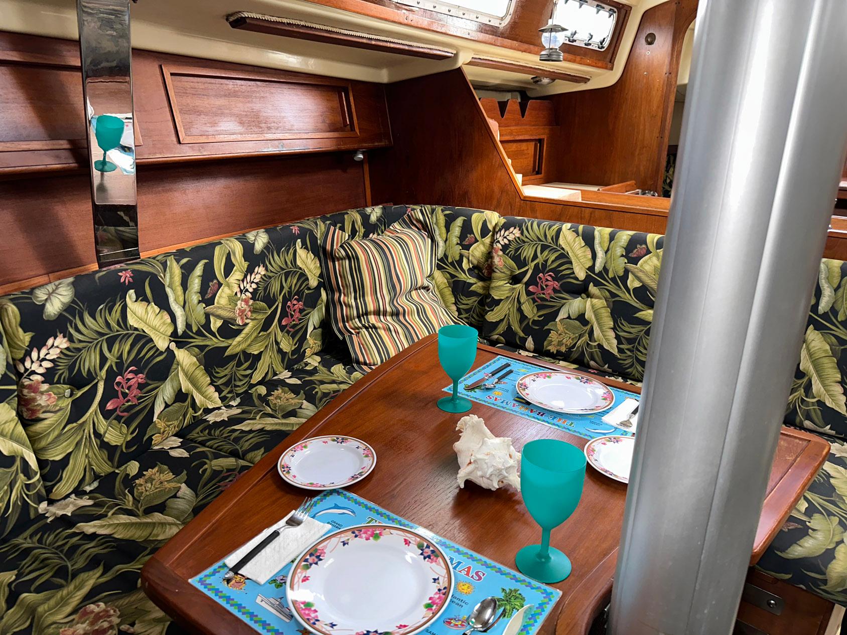 Cozy dining area in a 1987 Pearson 36-2 sailboat with floral upholstery and table setting.